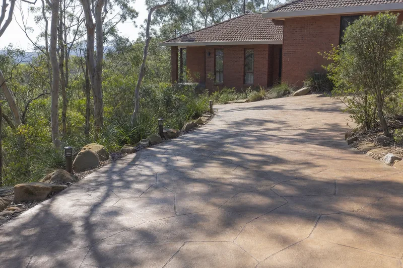 Stamped decorative concrete driveway at a brick-veneer home on a sloping Central Coast bushland block — driveways, Central Coast. Illustrative example.