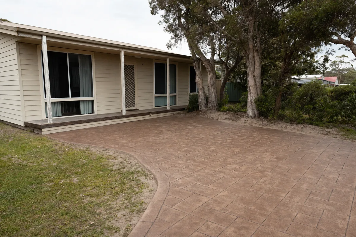 Stencilled concrete in a brick-pattern finish beside an older weatherboard Central Coast cottage — concreting, Central Coast. Illustrative example.